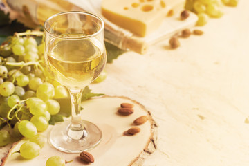 glass of white wine, nuts, cheese and grapes, tinted, copy space