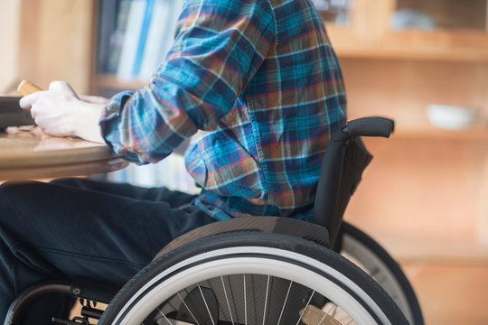 Young man using wheelchair connecting control panel and transformer at kitchen table