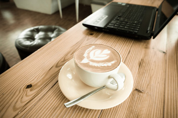 Latte coffee with laptop on old wooden table