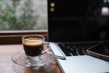 Espresso on work table with laptop and smart phone.