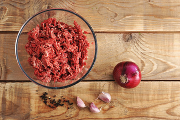 raw minced meat in a plate on wooden background