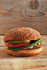 hamburger bun with sesame seeds, pickled cucumber, tomato, meat