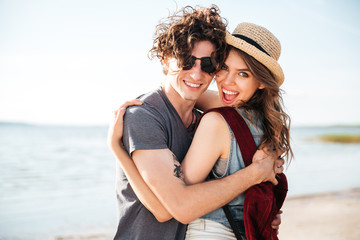 Cheerful couple standing and embracing on the beach