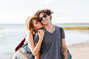 Couple with backpacks standing and kissing on the beach