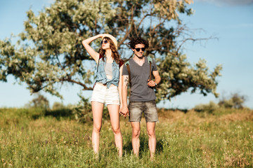 Fototapeta premium Young hipster couple standing against trees on the background