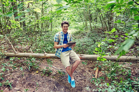 happy man with backpack and tablet pc in woods