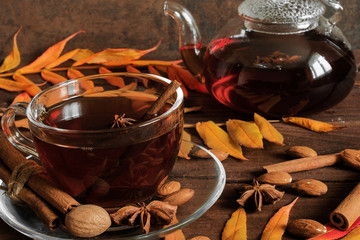 hot spiced tea in a glass cup with autumn leaves