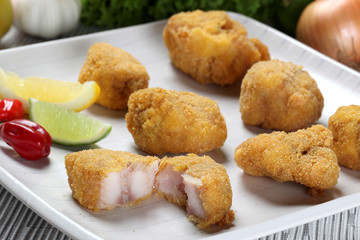 Fried fish portion served on plate with lemon