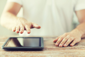 close up of male hands with tablet pc on table