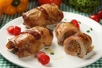 Chicken pieces with bacon. Vegetables in background