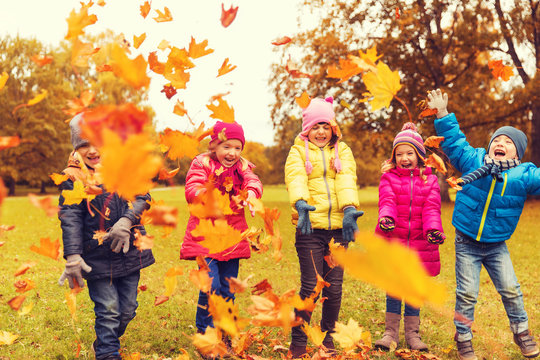 happy children playing with autumn leaves in park
