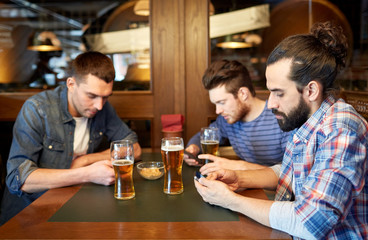 men with smartphones drinking beer at bar or pub