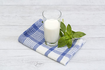 Milk in a glass and basil on a blue checkered napkin
