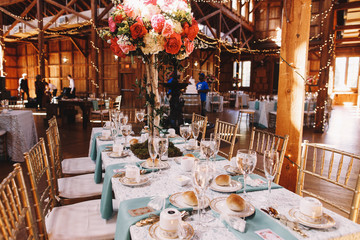 Fototapeta na wymiar Long dinner table covered with blue serviettes stands in the hal