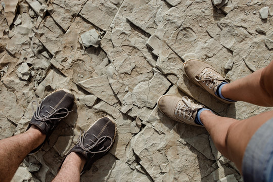 Female and male feet in casual shoes are standing on natural stone slabs. Hiking concept.