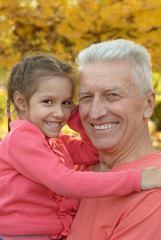 man with granddaughter in autumn park