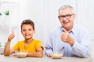 Grandfather and grandson are eating oatmeal at home. Healthy lifestyle.