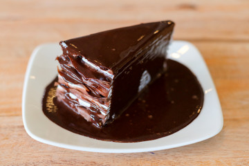 Chocolate cake on white dish and wood table in coffee shop.