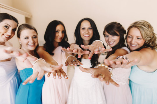 Bride and bridesmaids reach out their hands with bracelets