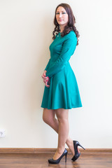 Office worker girl posing in a strict dress on wall background