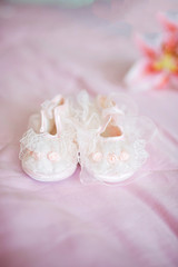 Little girl's shoes made of laces lie on the pink blanket