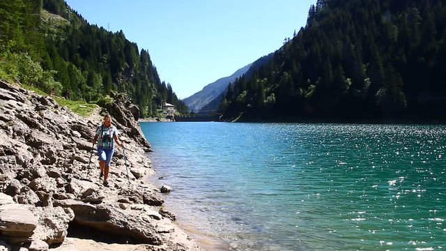 donna escursionista in riva ad un laghetto di montagna