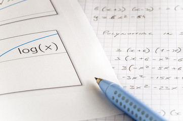 Pen on a Piece Paper with a Logarithmic Graph with and Mathematical Formulas in Background. 
