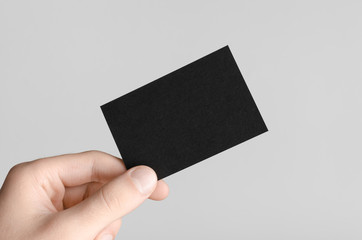 Black Business Card Mock-Up (85x55mm) - Male hands holding a black card on a gray background.