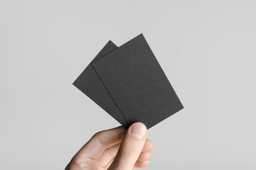 Black Business Card Mock-Up (85x55mm) - Male hands holding black cards on a gray background.