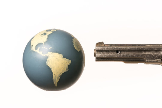 Barrel of a gun threatens the world globe.  On white background. With copy space text.