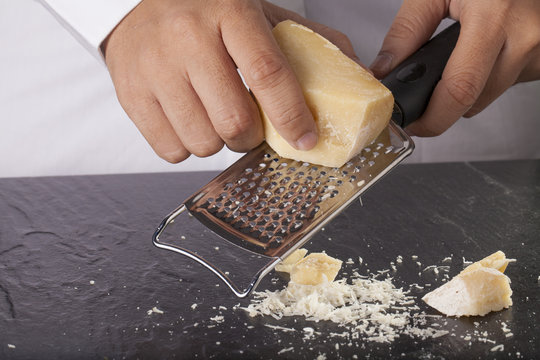 A Hand Grating Large Parmesan Cheese With A Grater