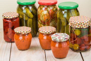 Assorted vegetable pickles in glass jars and roasted red pepper spread.