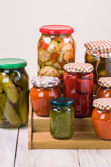 Assorted vegetable pickles in glass jars and roasted red pepper spread.