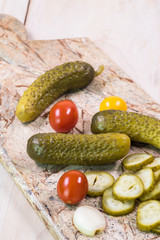 Dill pickles and cherry tomatoes pickles on a cutting board.