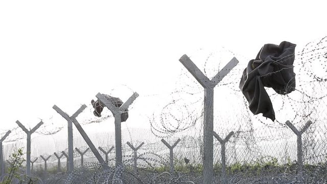 Clothes hang from a fence meant to keep the refugees away.
