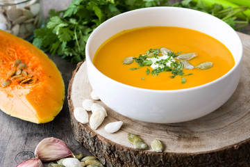 Pumpkin soup in bowl and ingredients on rustic wood
