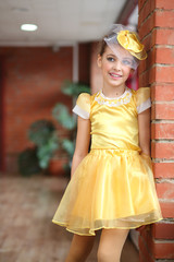 Portrait of beautiful girl in yellow satin dress near brick wall
