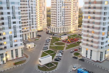 Courtyard with tall buildings, parking and playgrounds in modern residential complex Elk Island in the evening, top view