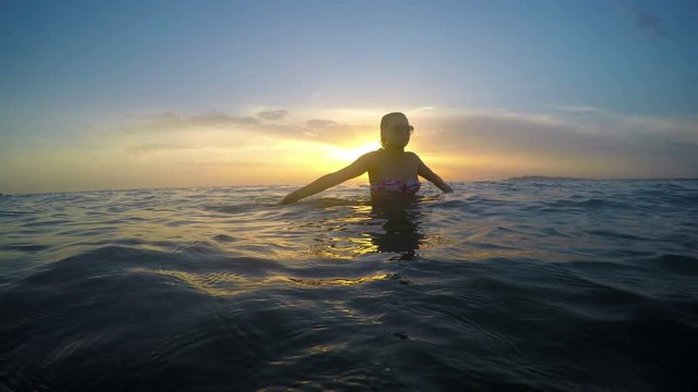 Girl walking out of water on the beach sunset
