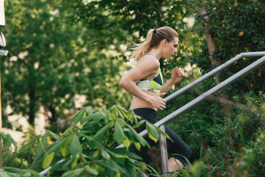 Young woman exercising outdoors, running up steps, Brooklyn Bridge Park, Brooklyn, New York, USA