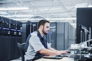 Caucasian technician using computer in server room