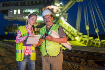 two workers check documents on background of career stacker
