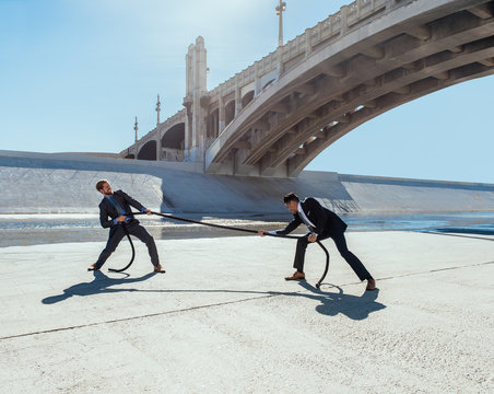 Businessman doing tug of war with rope, Los Angeles river, California, USA