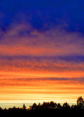 Fototapeta na wymiar Bright orange yellow and blue colors cloudy sunset sky shot vertical.