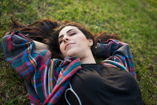 Young woman lying on grass, eyes closed