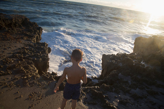 Rear view of boy watching ocean waves, Blowing Rocks Preserve, Jupiter Island, Florida, USA