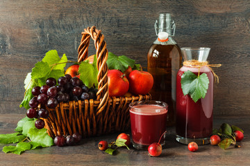 Apple and grape juice with fresh fruits on rustic table