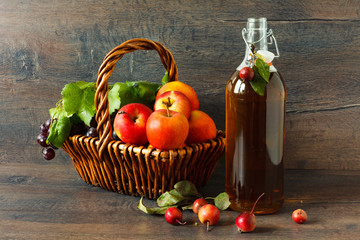 Apple juice in a bottle and small apples on wooden table