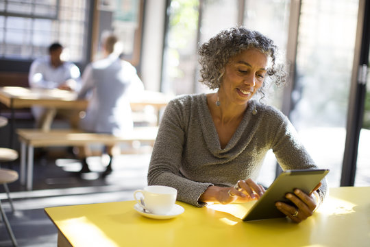 Older woman using digital tablet in cafe