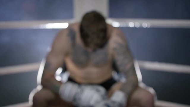  Aggressive fighter sits in corner of ring, psyching himself up for the fight.